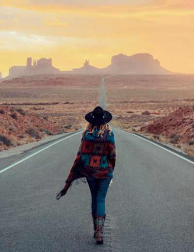 cowgirl walking on long stretch of highway in arizona